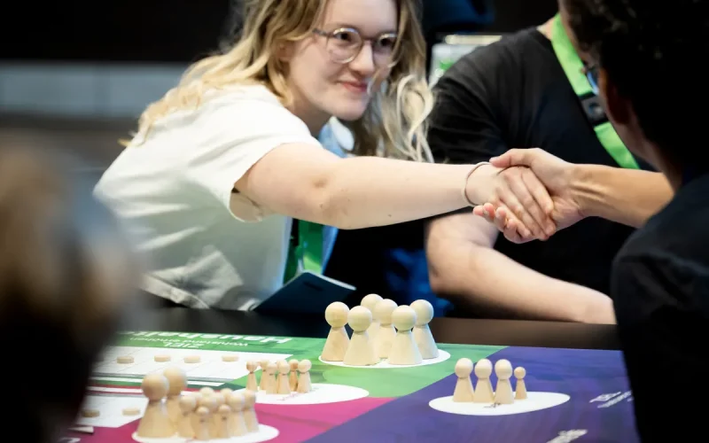 Personen reichen sich die Hand am Spieltisch