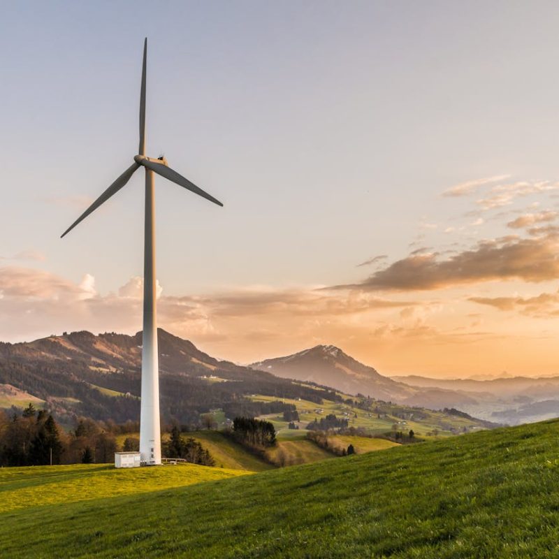 Feld in den Bergen mit Windkraftwerk